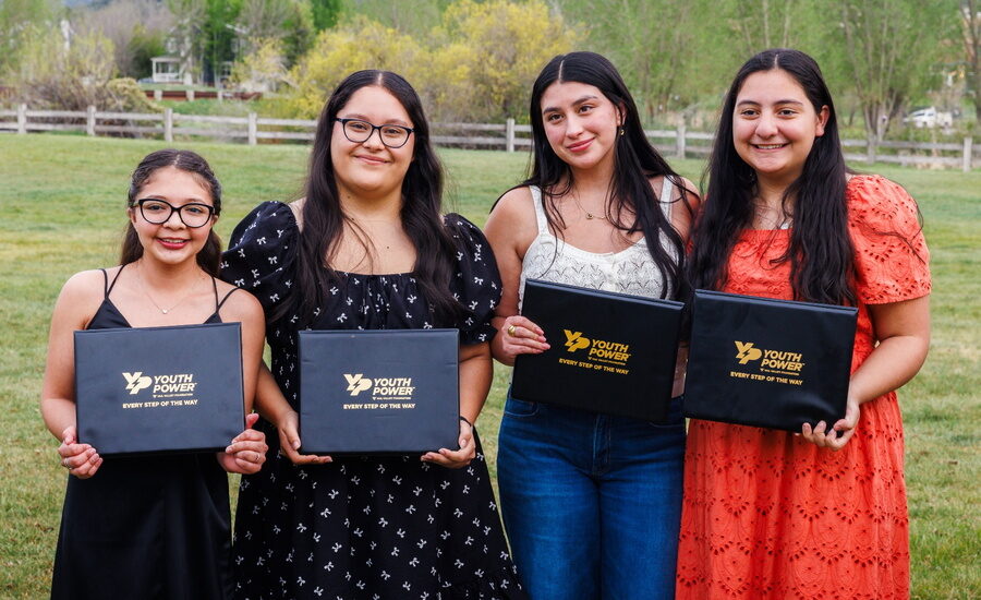 Youth holding up Youth Power diploma folders during scholarship ceremony